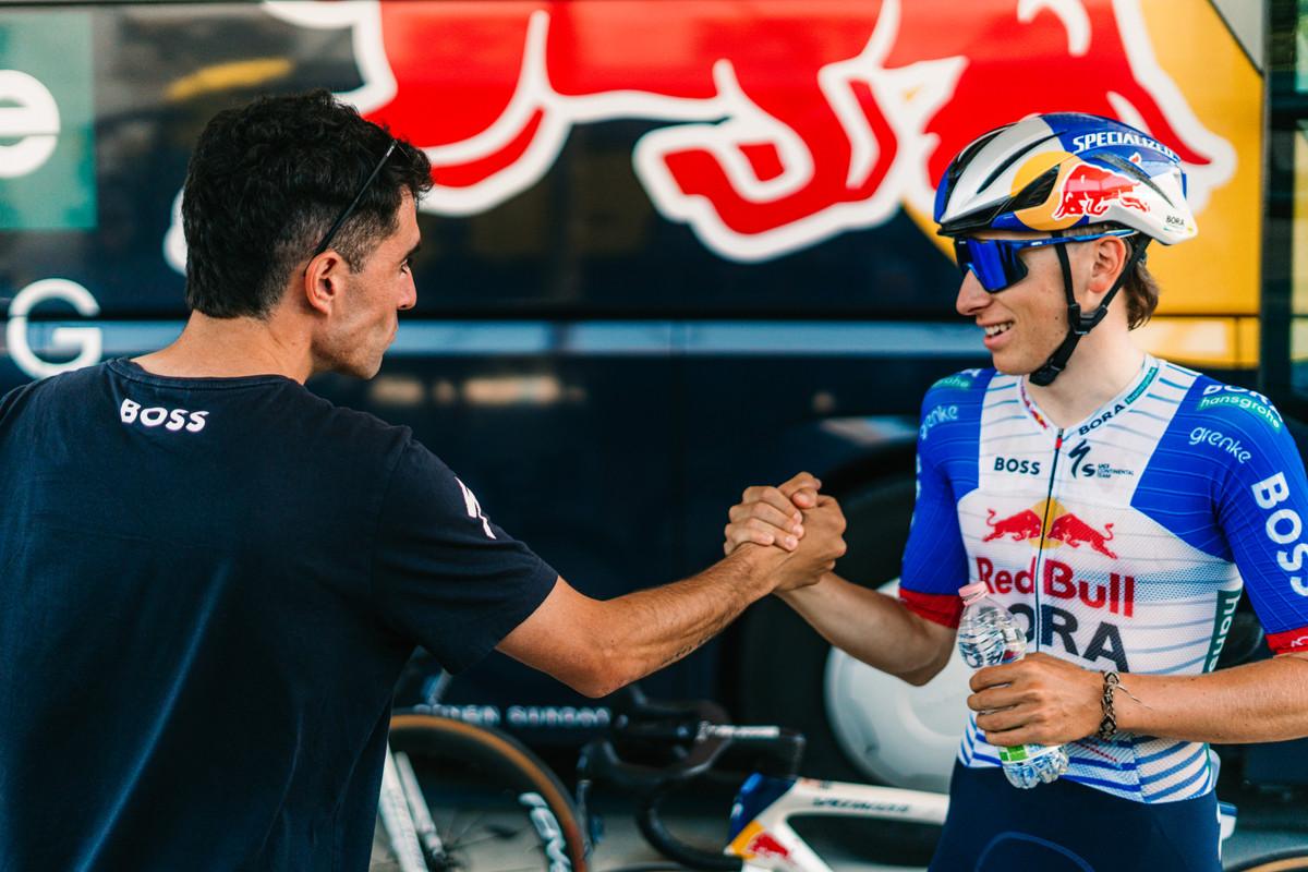 Gustave Blanc shaking hands with a staff member in front of the Red Bull – BORA – hansgrohe bus